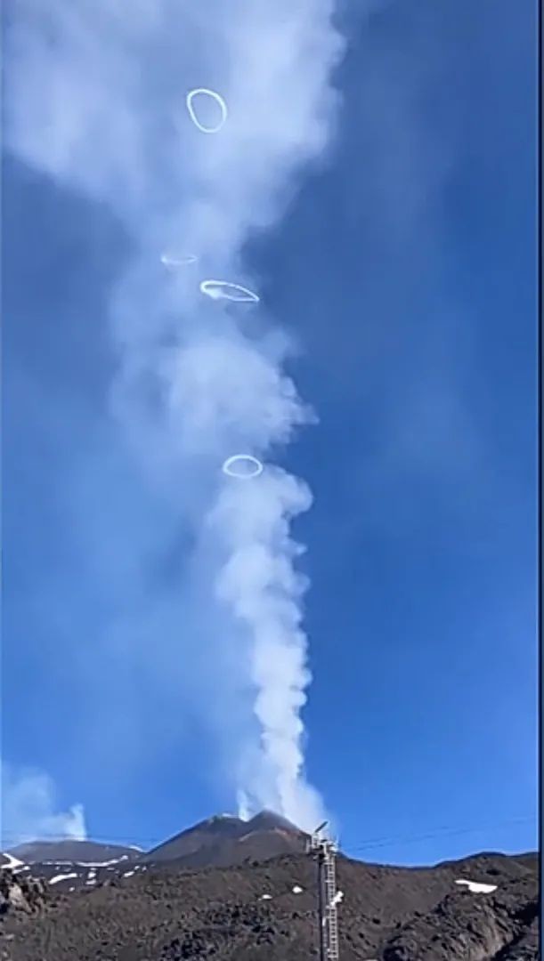 Picture of Mt. etna with four circular smoke rings above it.