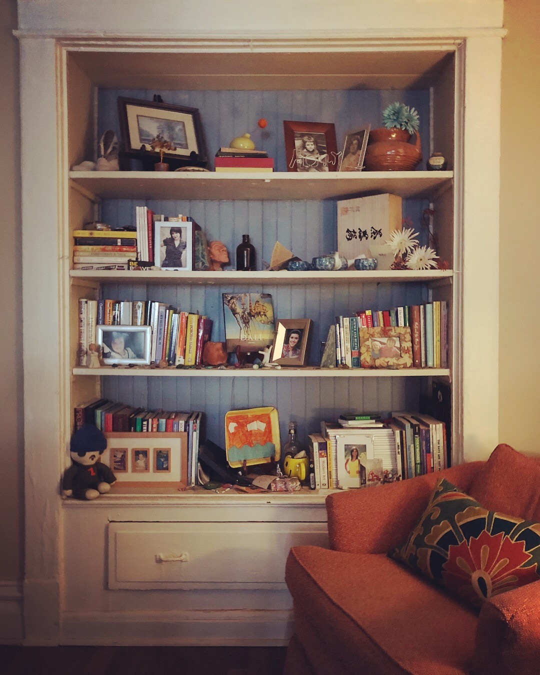 One of my bookshelves in my apartment. At right is an upholstered chair tucked into one of my reading nooks. 