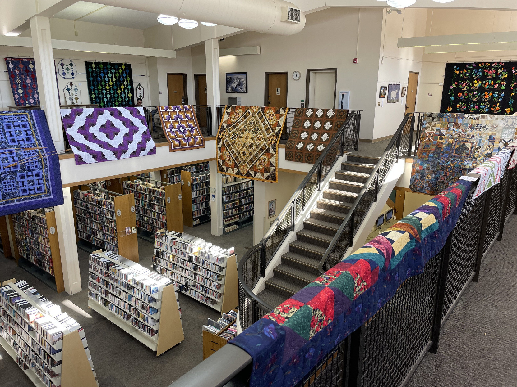 The view from the second floor of our local library with many colorful and intricate quilts on display as part of an art exhibition.