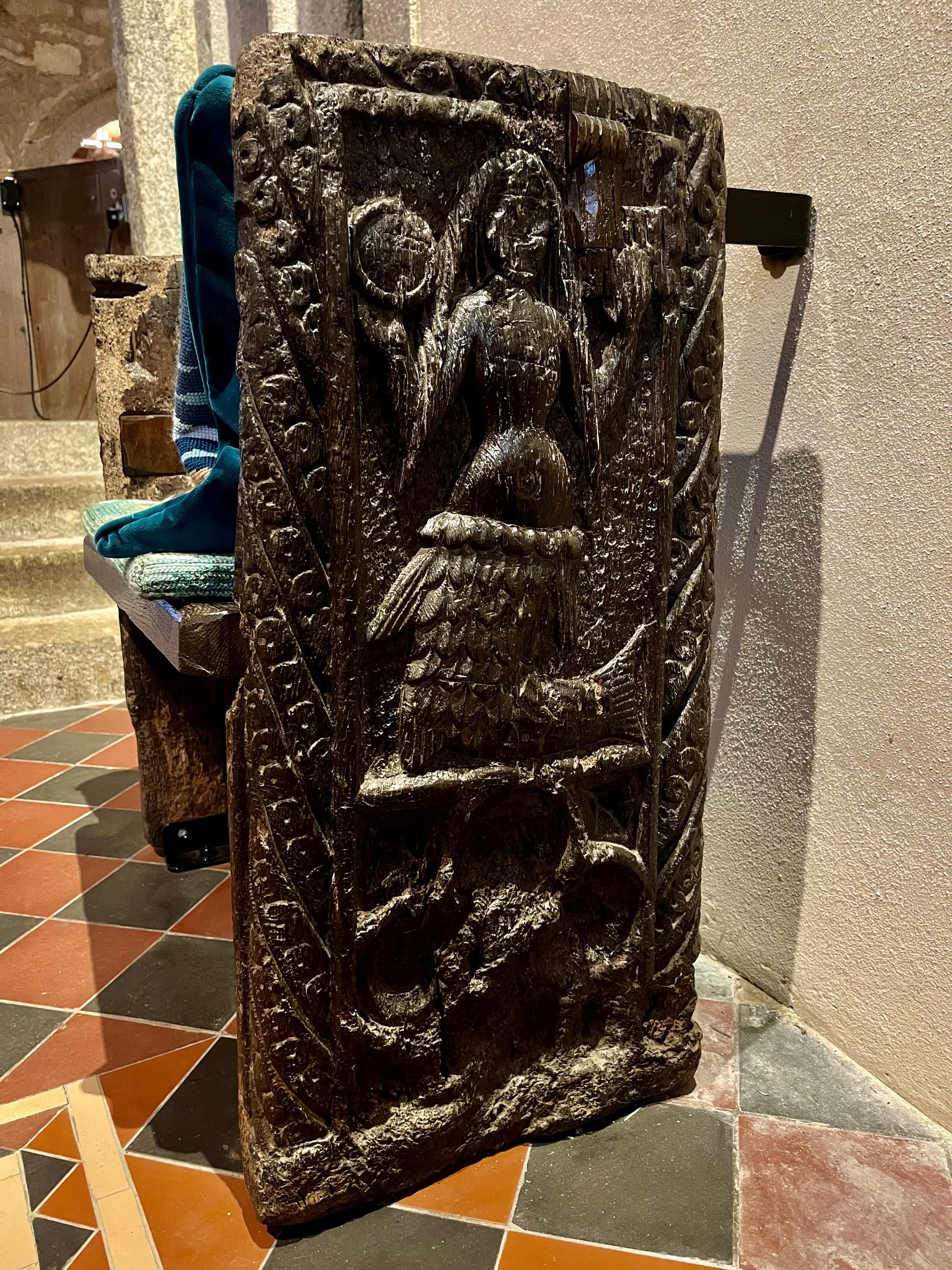 A wooden chair with a carved panel depicting a mermaid.