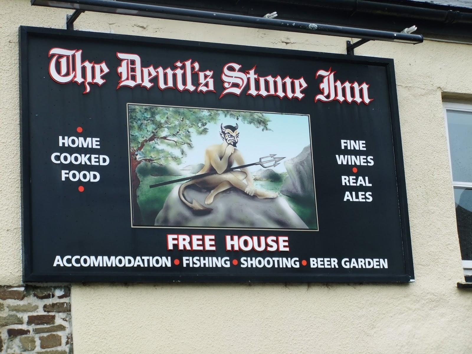 The painted sign for The Devil's Stone Inn, showing the famous stone and a cartoon devil sat on it