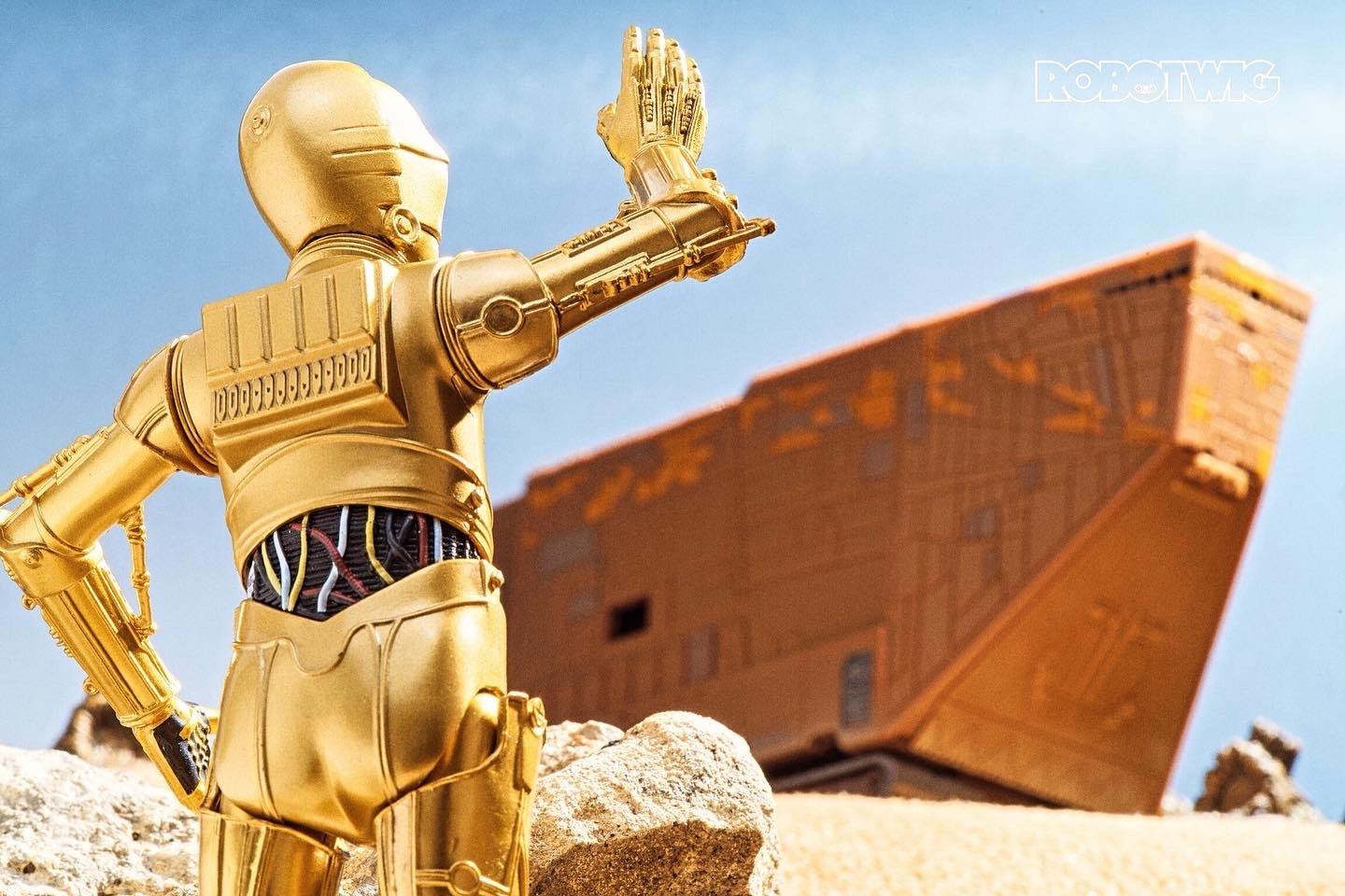 C3P0 attempts to flag down the Jawas in the desert his right arm raised in the air