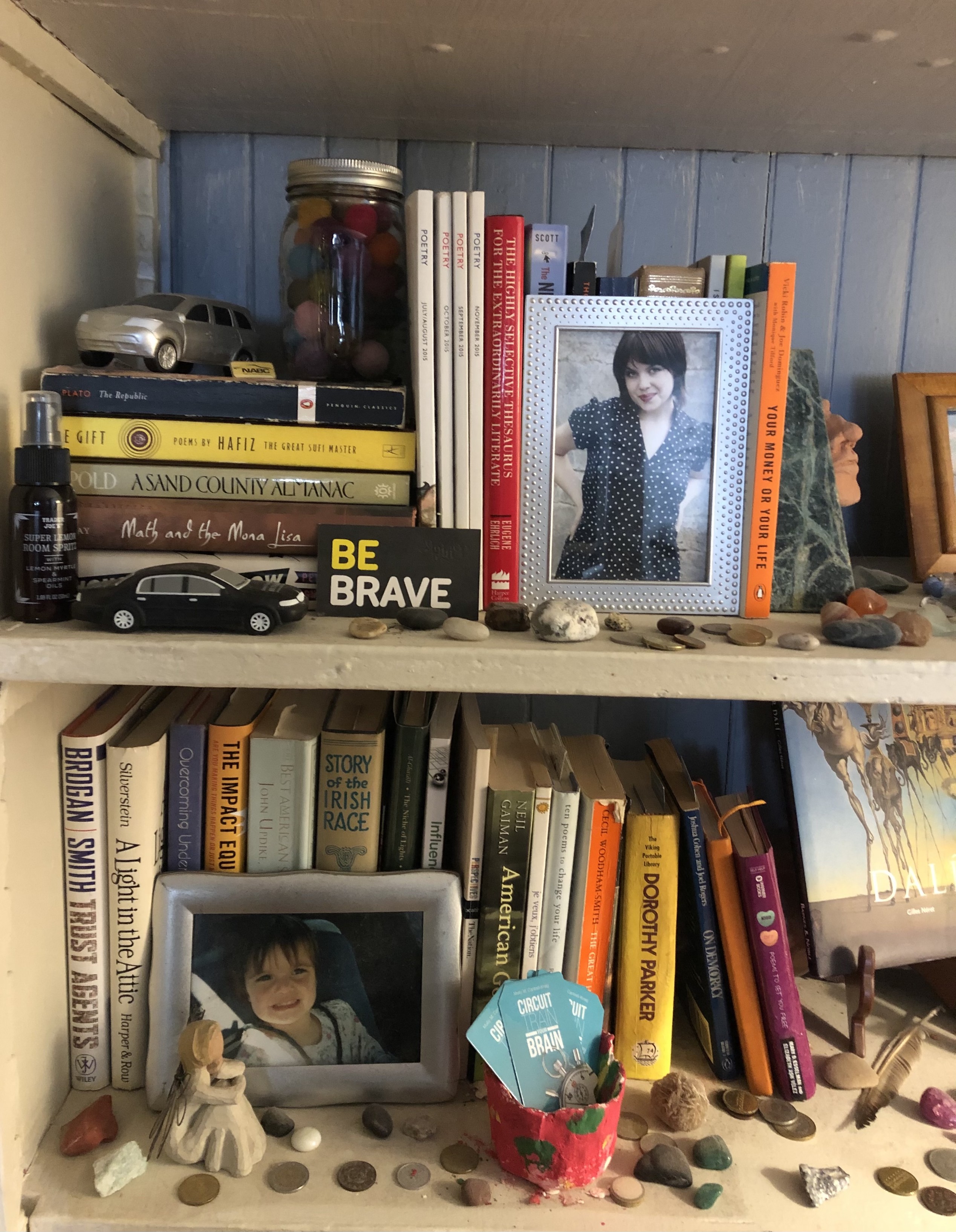 Close up of one of the shelves of the previous picture. Various titles include poetry, figurines, photos of my kids and rocks that I collect from my journeys. 