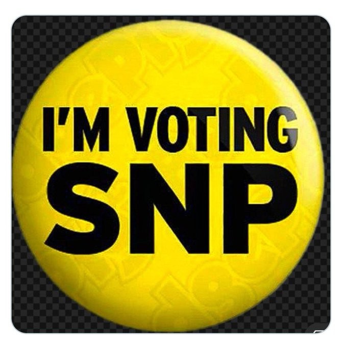 A yellow lapel badge with the worda "I'm Voting SNP in black letters...