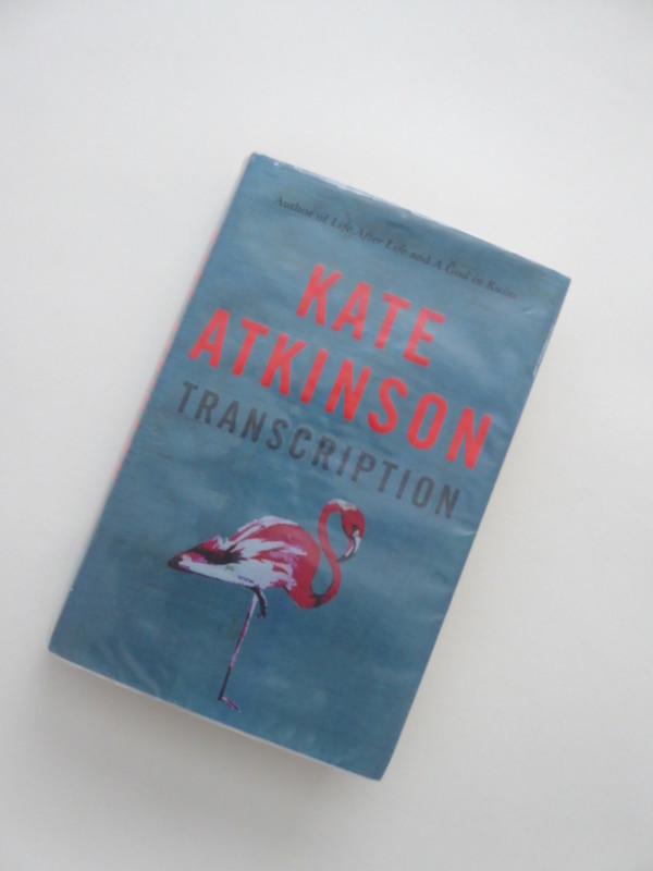 A photo of the hardback book 'Transcription' by Kate Atkinson against a light grey background..

The book cover is mid blue with the author's name in bright red upper case lettering and the book title in black upper case lettering.

Beneath is an illustration of a pink and white flamingo.

* Another Duchess of Spring Alt-text production ™
