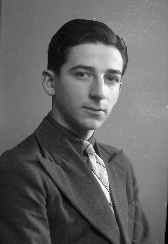 A portrait ID photo of a youngman in a suit. He has dark short hair.