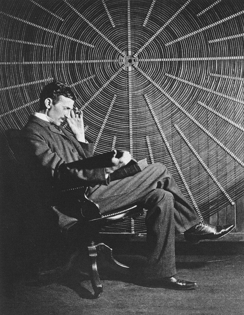 Nikola Tesla (1856-1943) thinking.

Tesla is seated in a dimly lit study or laboratory. He wears a dark, tailored suit, complete with a high-collared white shirt and a neatly tied bowtie, reflecting his elegant style. His slender frame and sharp features are illuminated by soft, focused light, emphasizing his high cheekbones, deep-set eyes, and slightly furrowed brow.