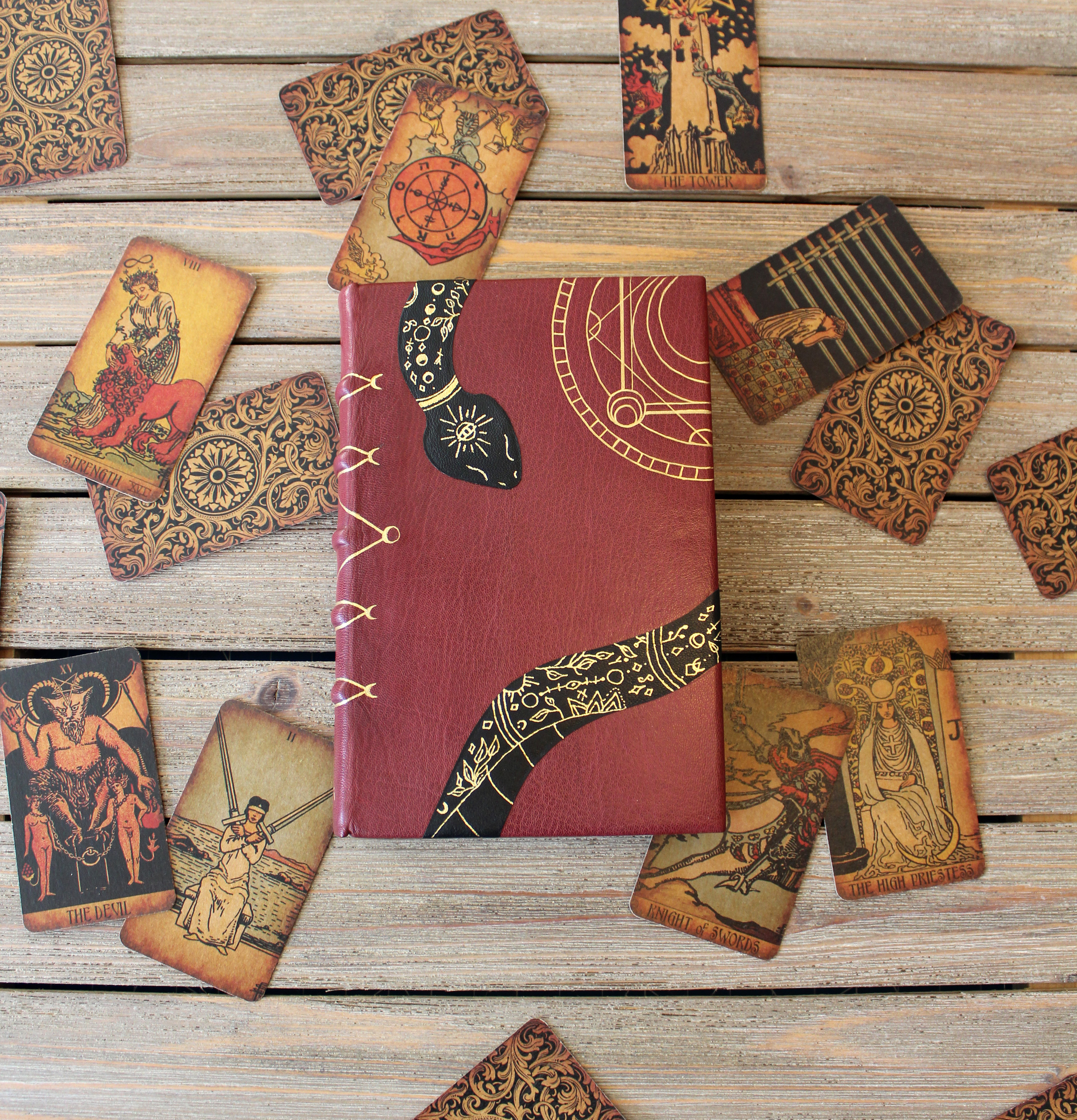 A red leather book lying amongst tarot cards. 