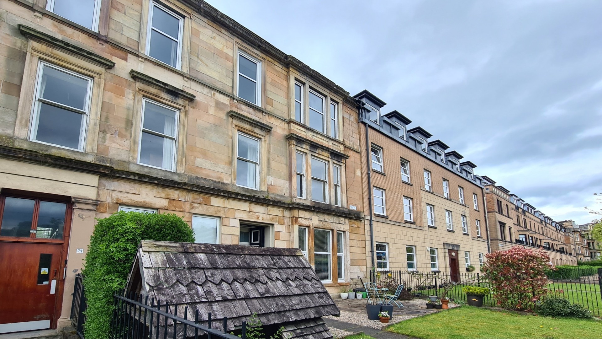 A street lined with residential houses. In the foreground and the distance are old sandstone tenements, while between them are newer brick-built flats.