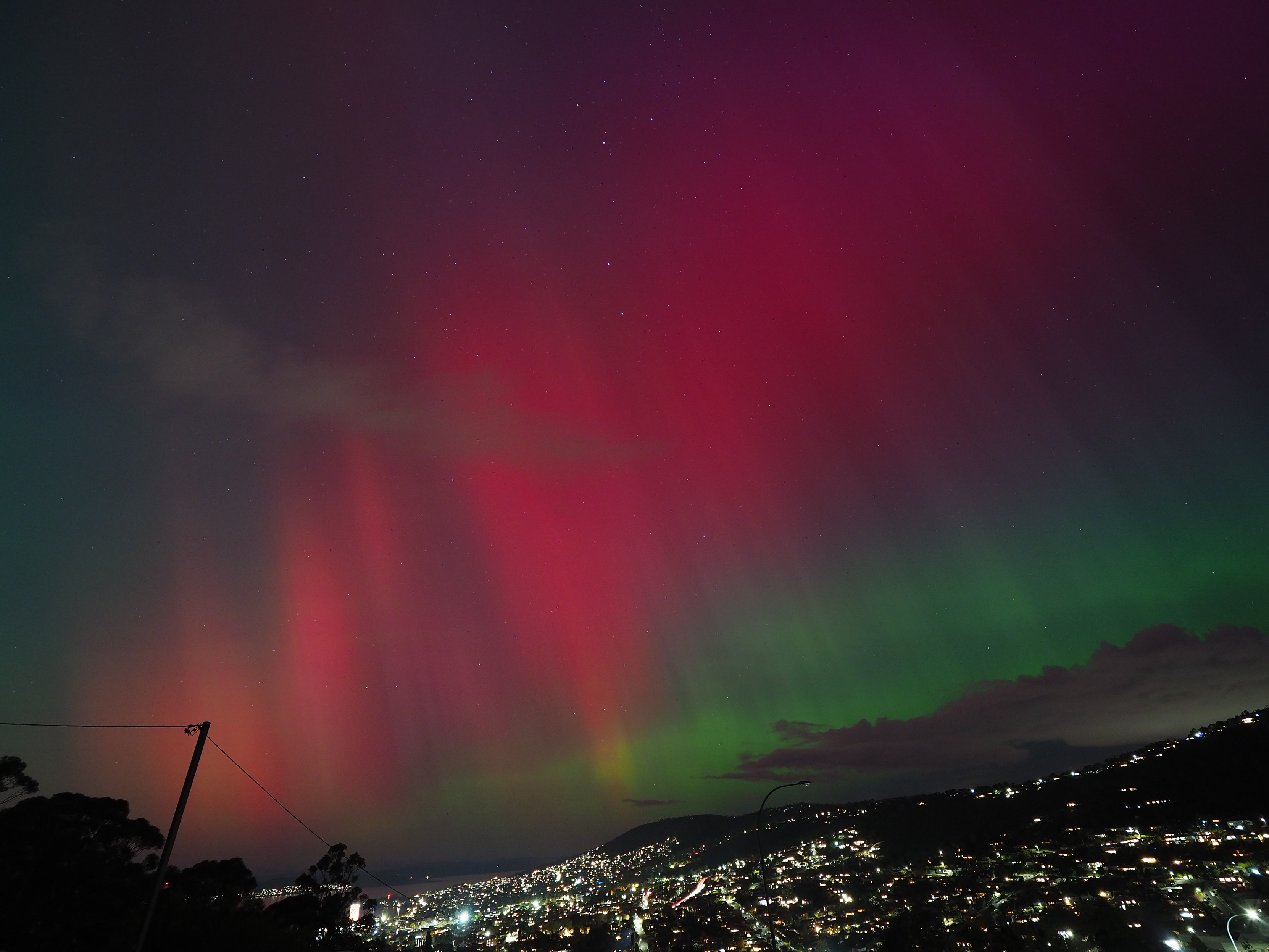 Red, green and purple aurora over the lights of South Hobart and Mt Nelson