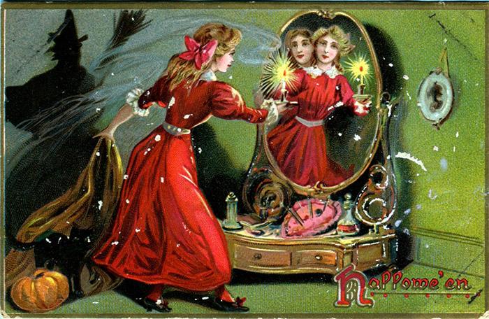 A vintage Halloween postcard picturing a ghostly vision in a mirror by candlelight