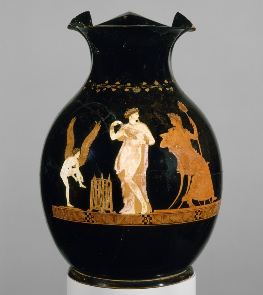 Description from the museum: “Pompe, whose mantle only accentuates her nudity, holds a wreath and looks toward Dionysos, seated and wearing a diadem. The winged Eros adjusts his sandals as though preparing to depart. The gilt openwork basket on the ground is the type used in religious processions to carry sacrificial implements to the place of sacrifice. This procession must be part of an Athenian festival in honor of Dionysos, probably the Anthesteria, which culminated in the sacred marriage of the god to the wife of the archon basileus, a high official representing the ancient Athenian kings. This is one of the most refined vase-paintings in the entire collection. The graceful figure of Pompe reflects full-scale statues of Aphrodite in the nude that were being carved in the wake of the first nude statue of the goddess created by Praxiteles in the mid-fourth century B.C.”