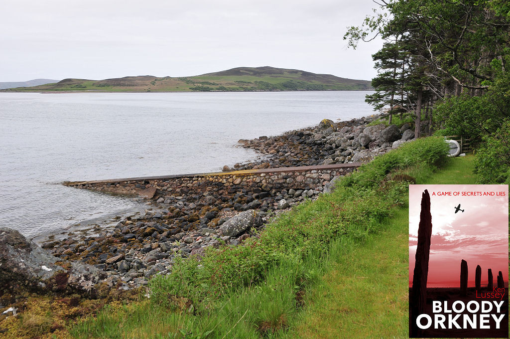 This modern view shows Gruinard Island in the distance with the shore of Gruinard Bay in the foreground. There’s a sloping jetty leading into the bay and a stand of trees on the right. The front cover of ‘Bloody Orkney’ is shown in the bottom right corner.