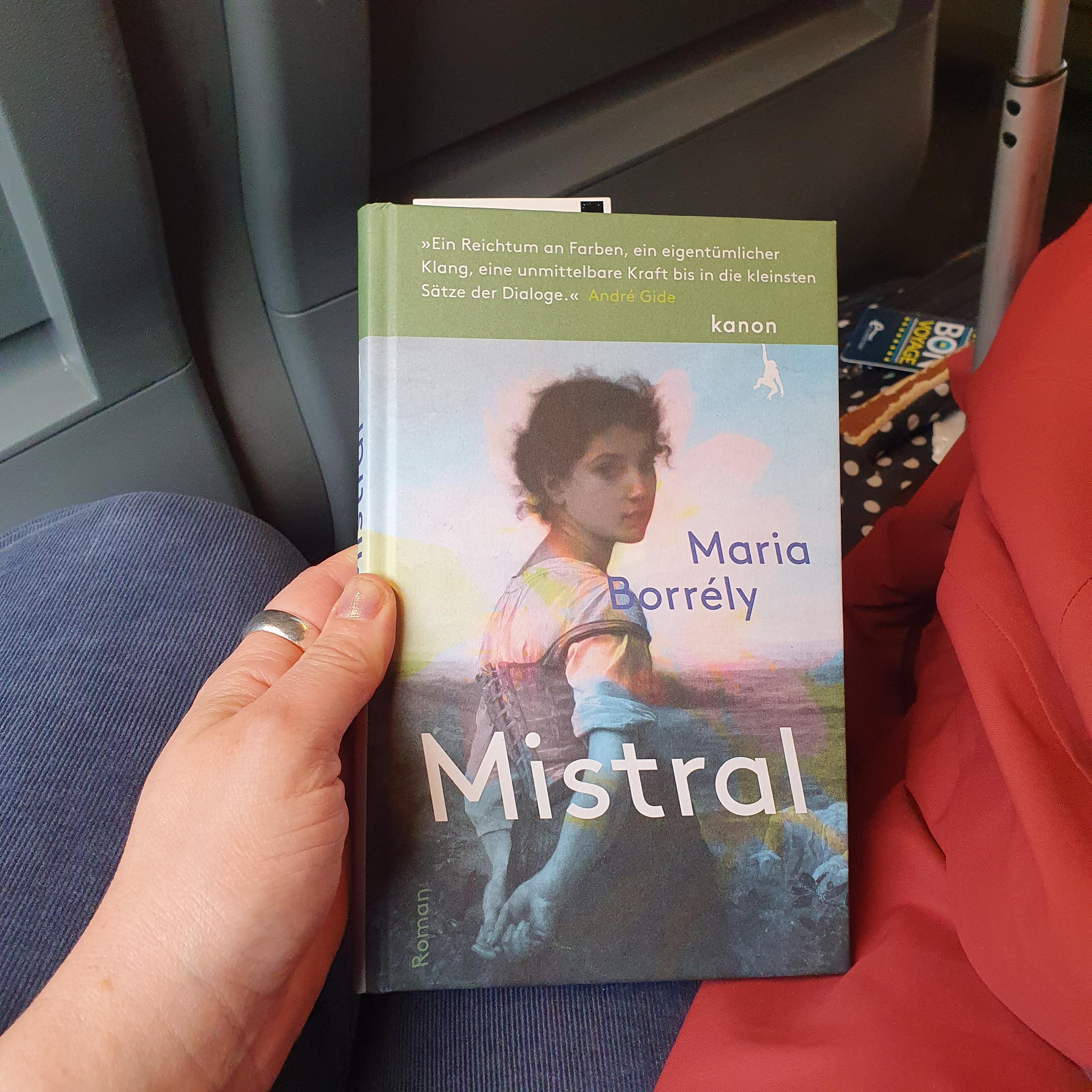 My hand holding the (German language) book "Mistral" by Maria Borrely in a German regional train. 