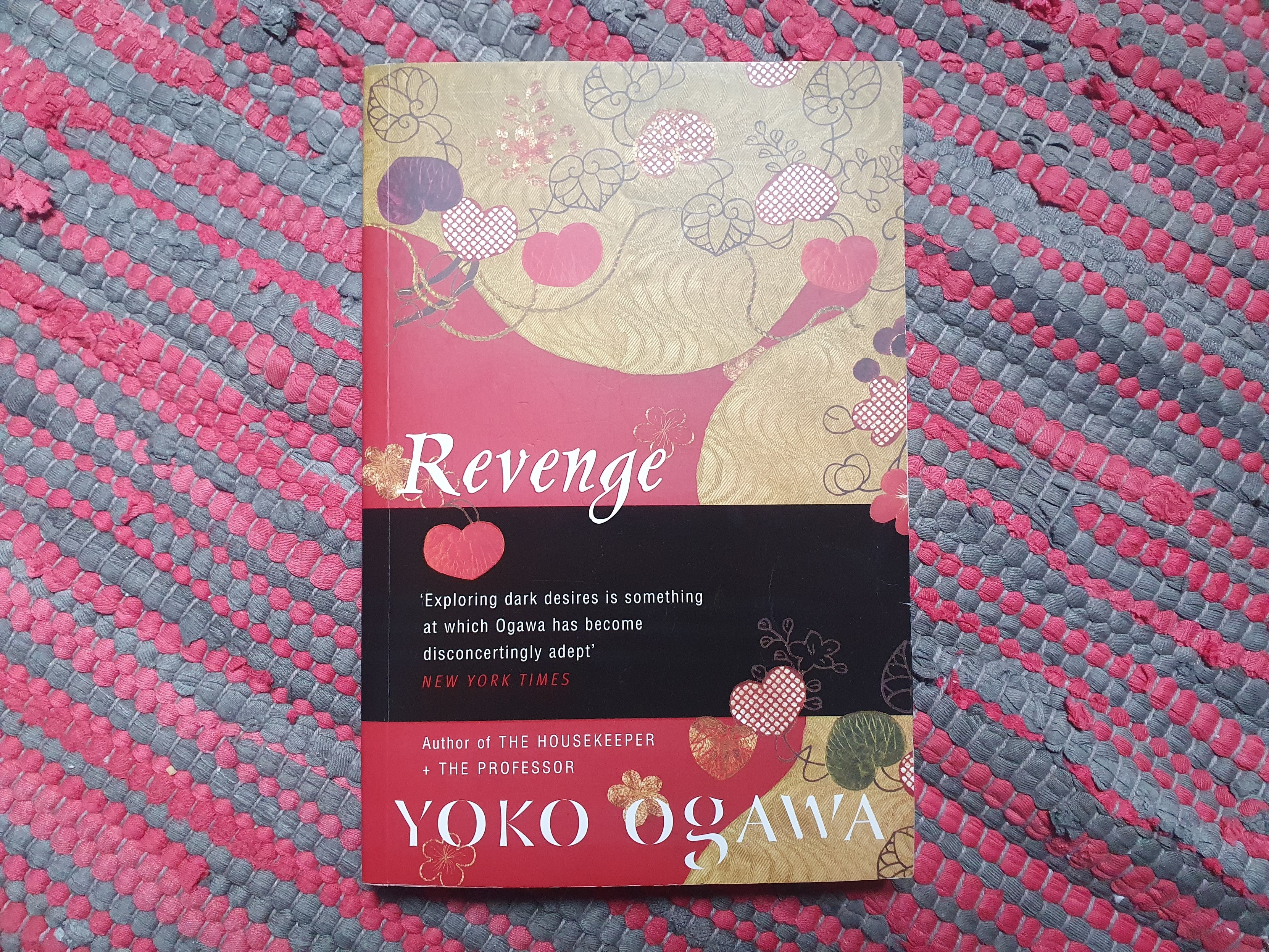 The book "Revenge" by Yoko Ogawa on a red rag rug. 