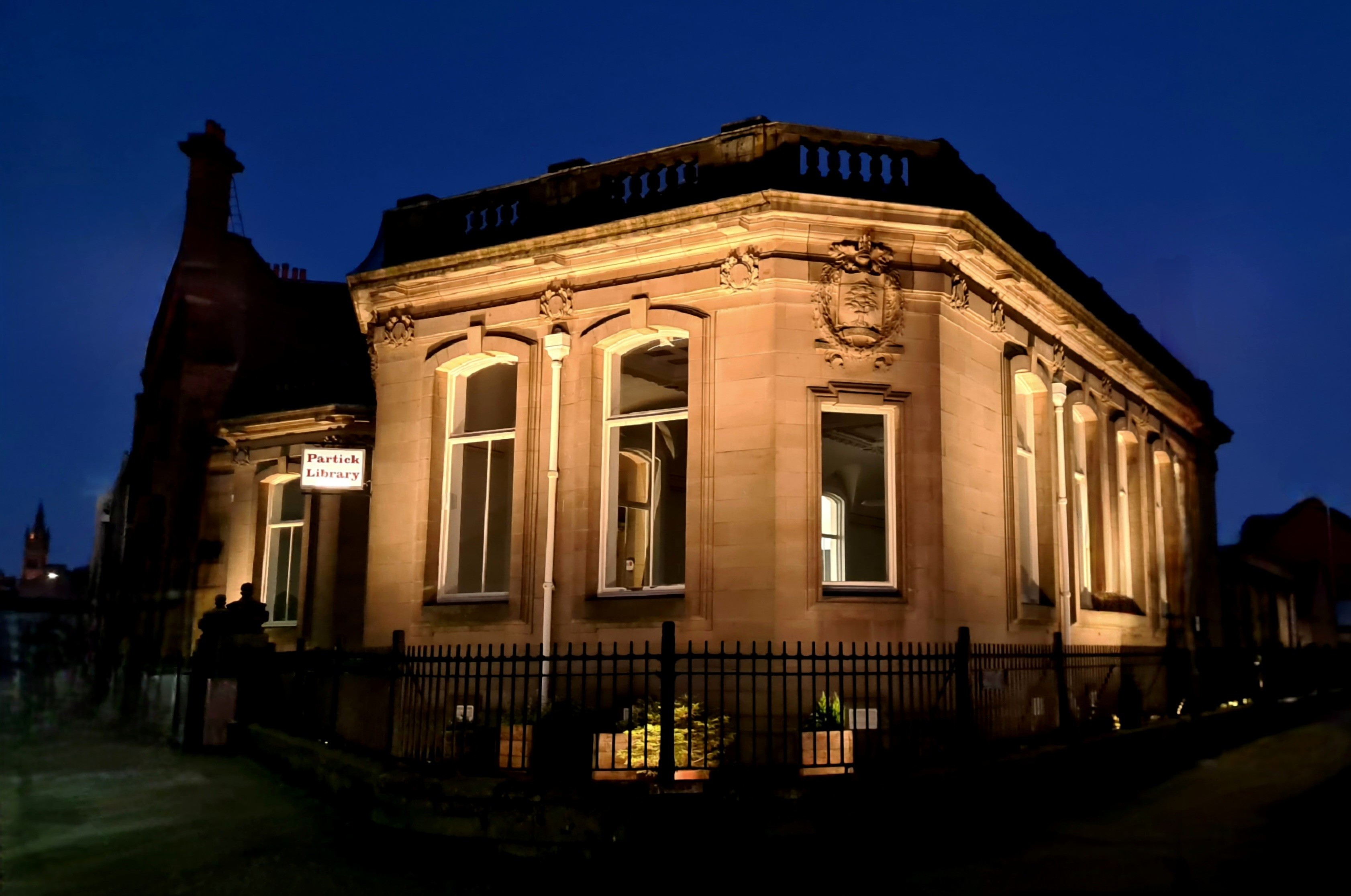 A stone library building lit up at night against a dark blue sky.