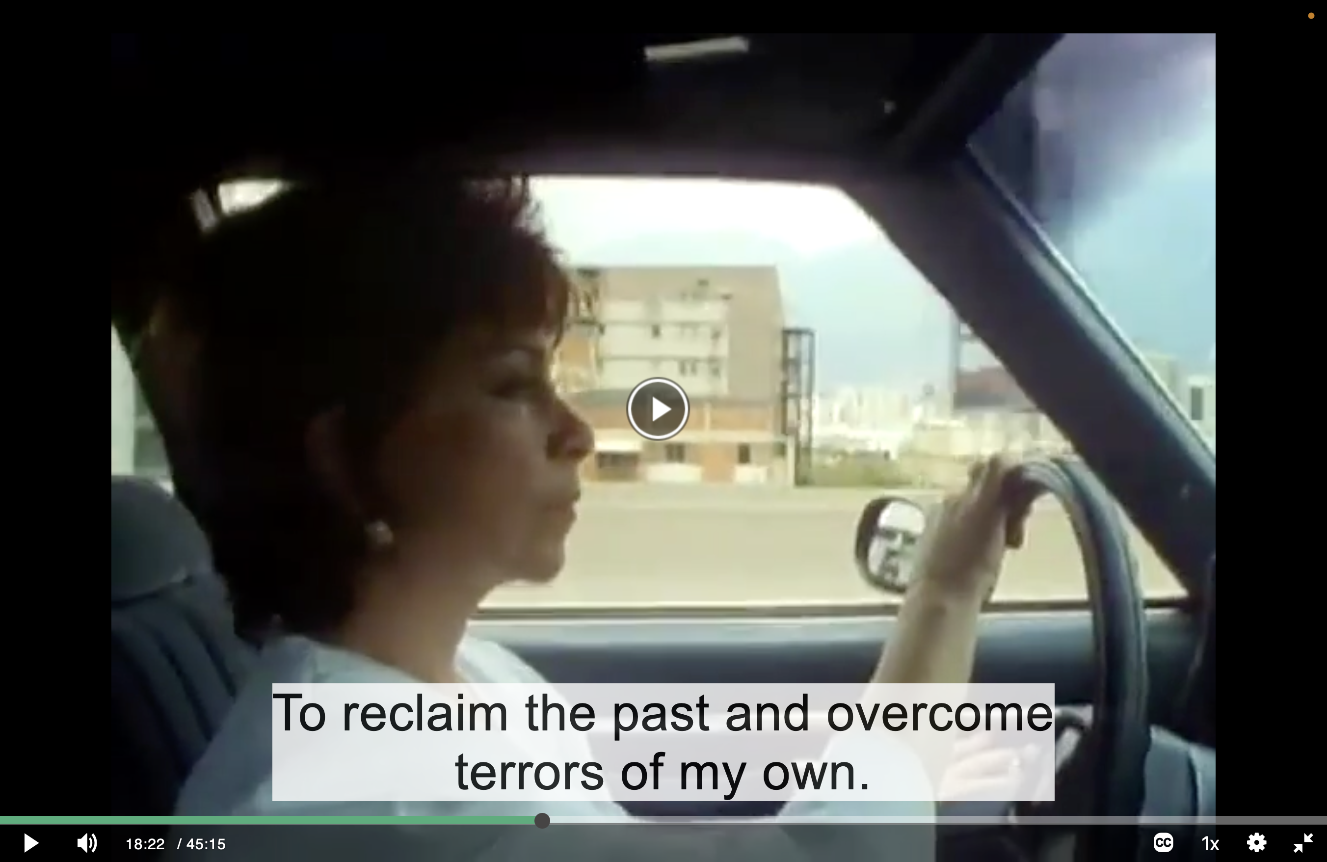 Screenshot of a woman, Isabel Allende, 45 years old in 1988, with a fashionably short haircut. She is in the drivers' seat of a car with her hand on the steering wheel, looking out the window. The city of Caracas, Venezuela is in the background. The subtitle reads "To reclaim the past and overcome terrors of my own."