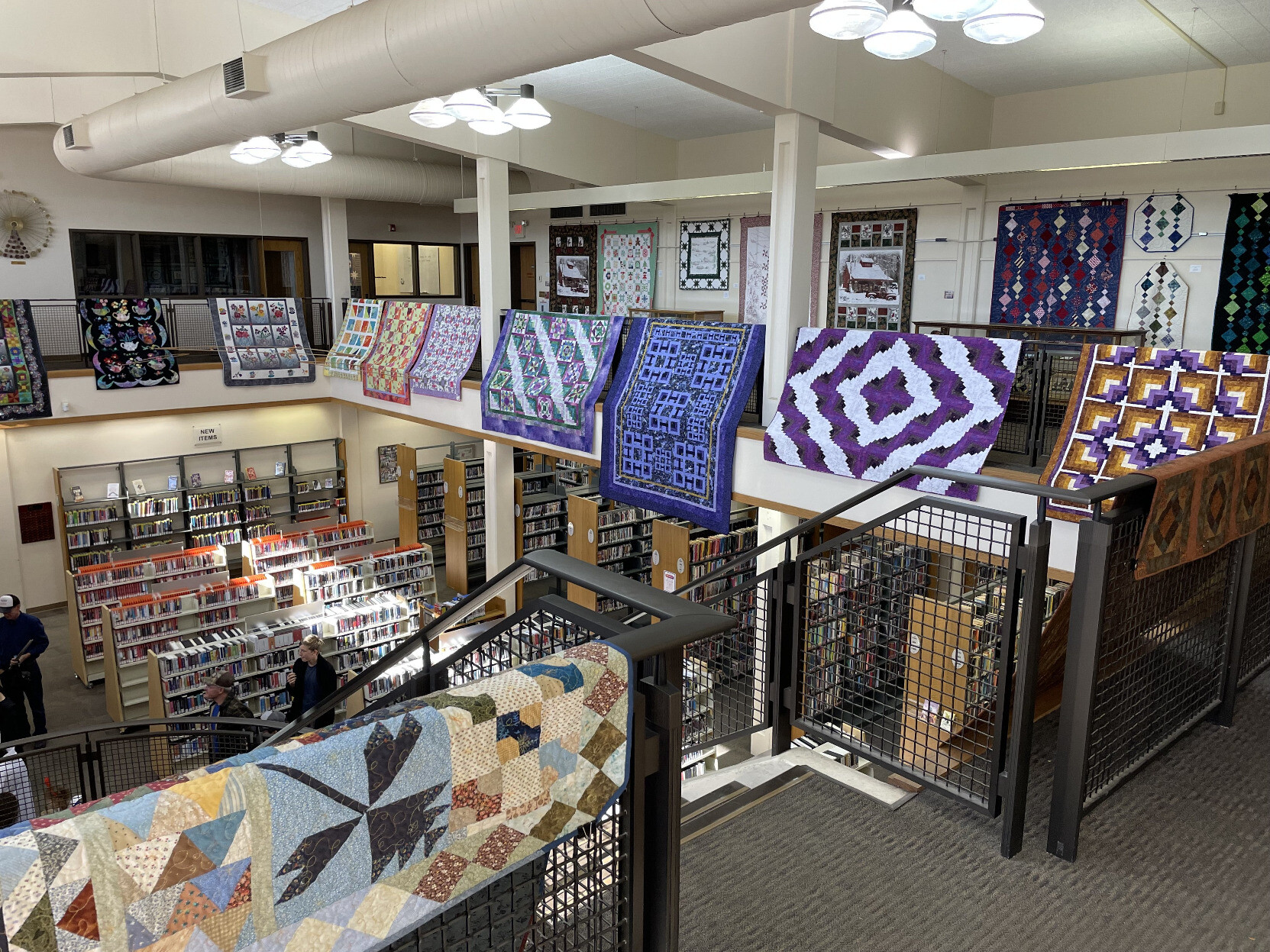 The view from the second floor of our local library with many colorful and intricate quilts on display as part of an art exhibition.