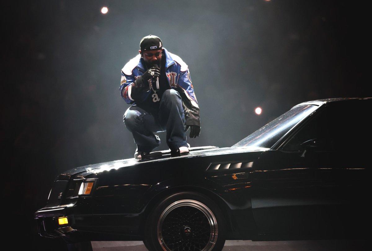 Kendrick Lamar standing on a black Buick GNX car during his Super Bowl halftime show. 