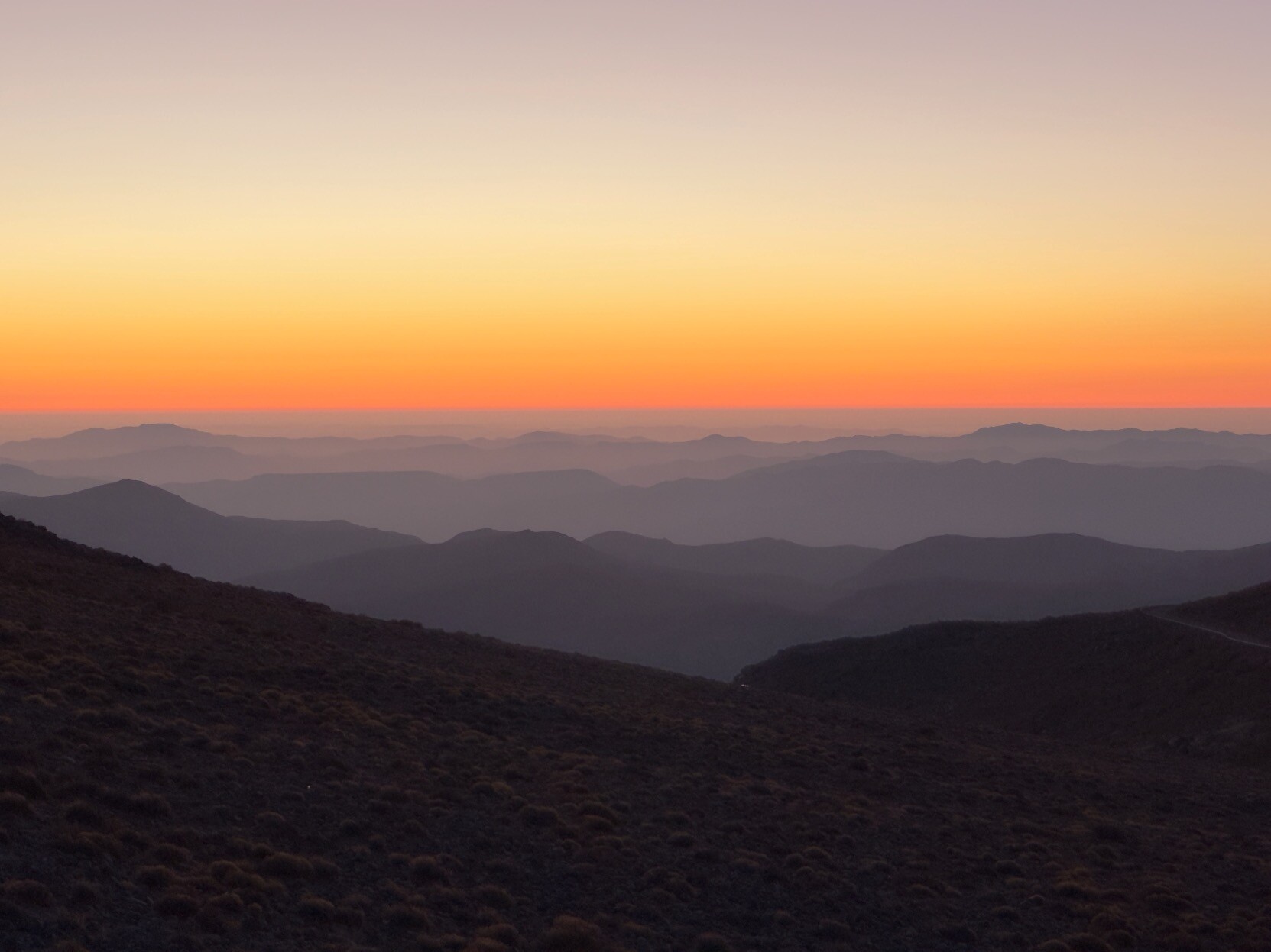 The orange line of the sunset cuts the image in half horizontally.  From the foreground layers of mountains changing from dark, to blue to orange are seen.