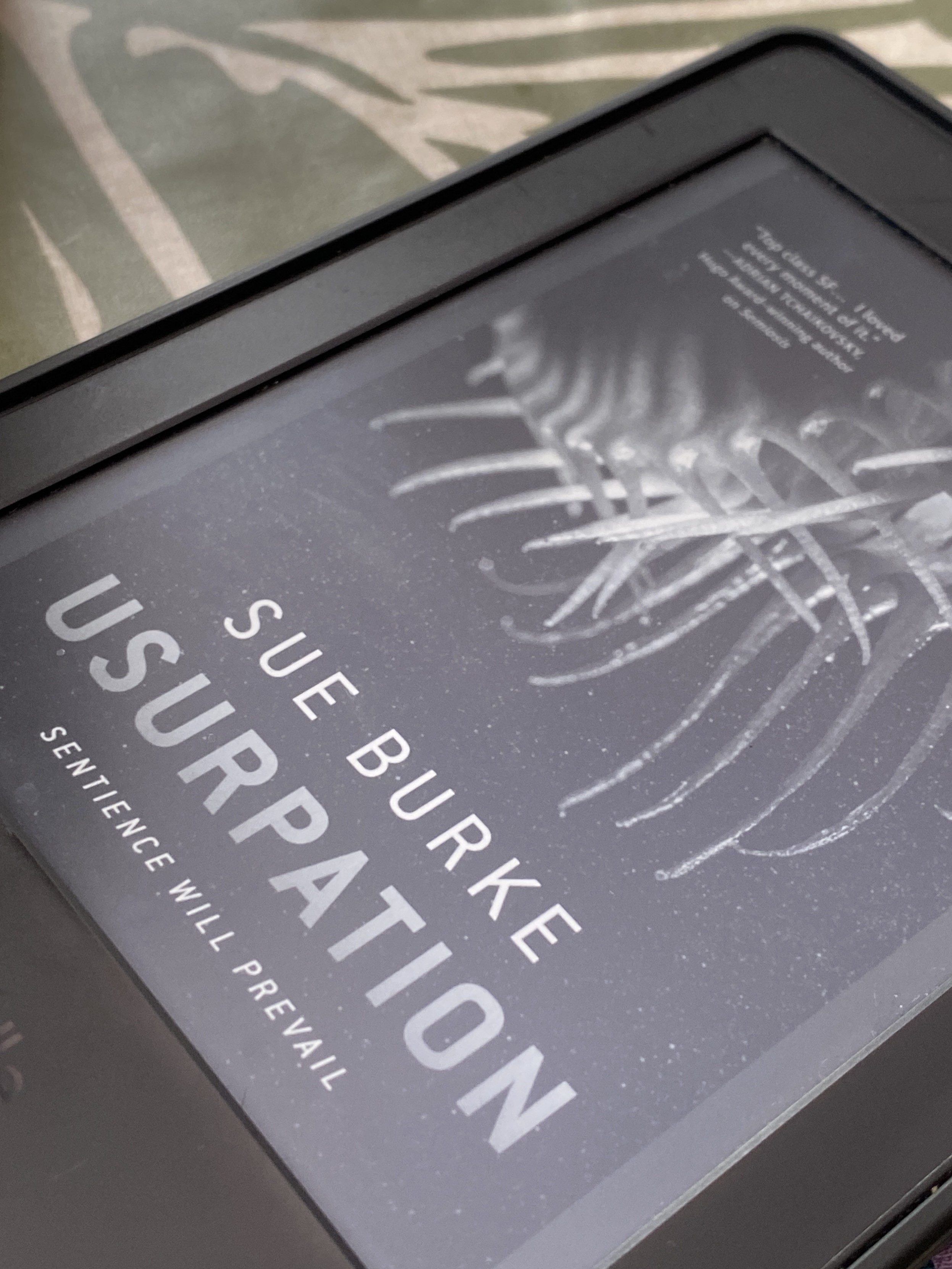 An e-reader (monochrome) displaying the cover of Usurpation by Sue Burke. Subtitle: “Sentience will prevail”. Cover photograph of a Venus Flytrap.