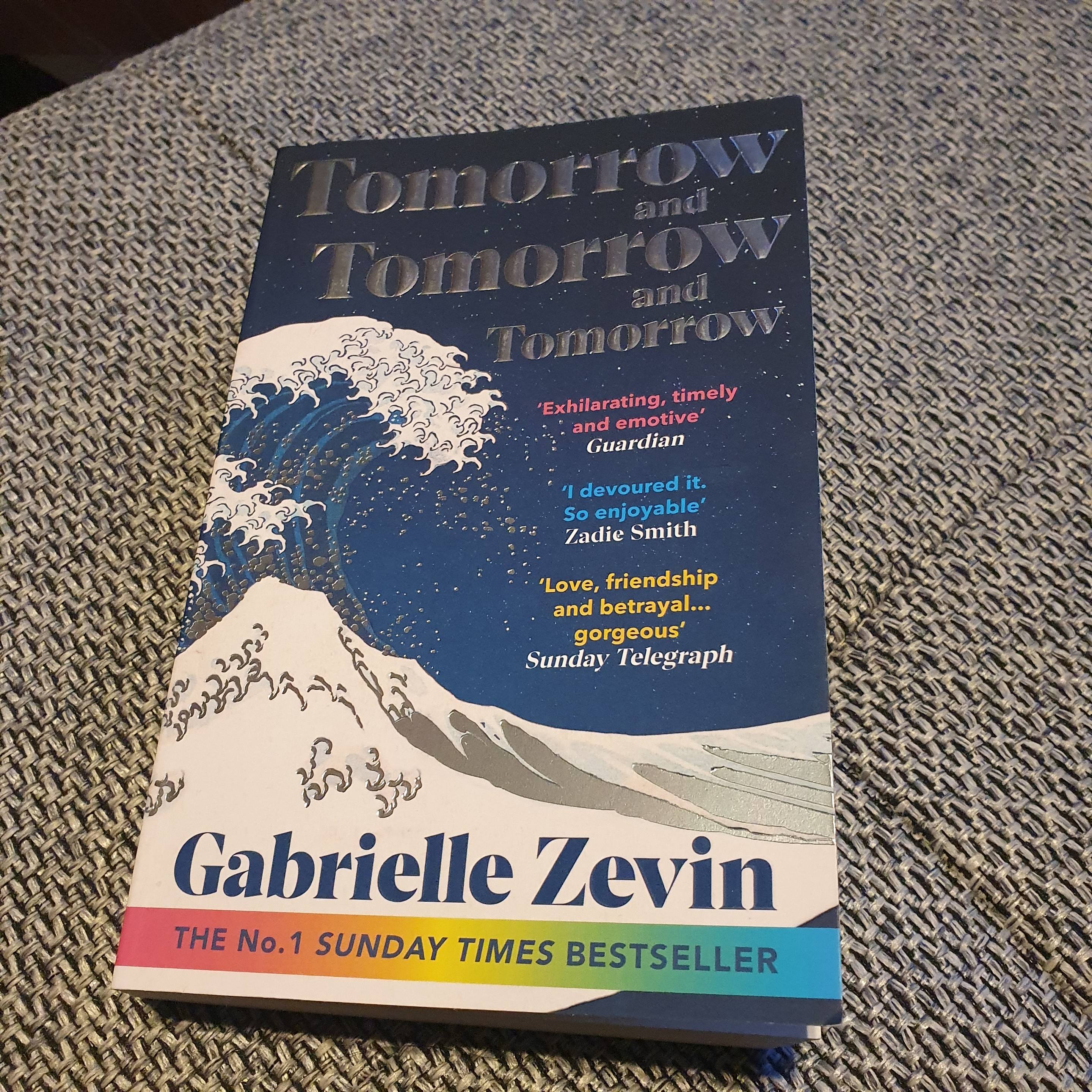 Gabrielle Zevin book "Tomorrow and tomorrow and tomorrow" on my couch, a background we've seen often in the #AboutToday series. 