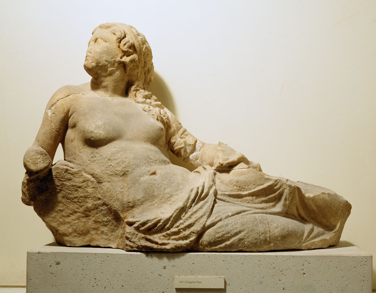 Description from the museum: “The reclining female figure supports itself with its right hand on a rock. The cloak has slipped down to the hips, in the left hand the figure originally held a drinking vessel. According to one interpretation, the gable showed the handing over of the founder of the Samothracian mysteries, Aetion, which would make the female figure the personification of the main mountain of the island.”