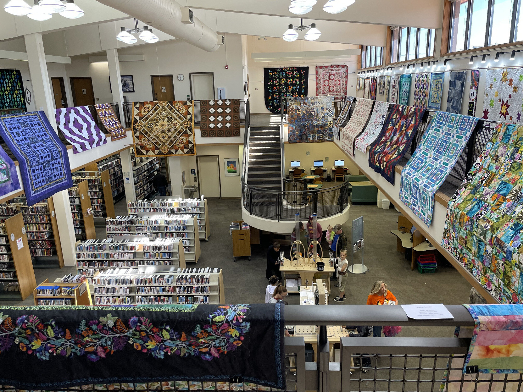 The view from the second floor of our local library with many colorful and intricate quilts on display as part of an art exhibition.