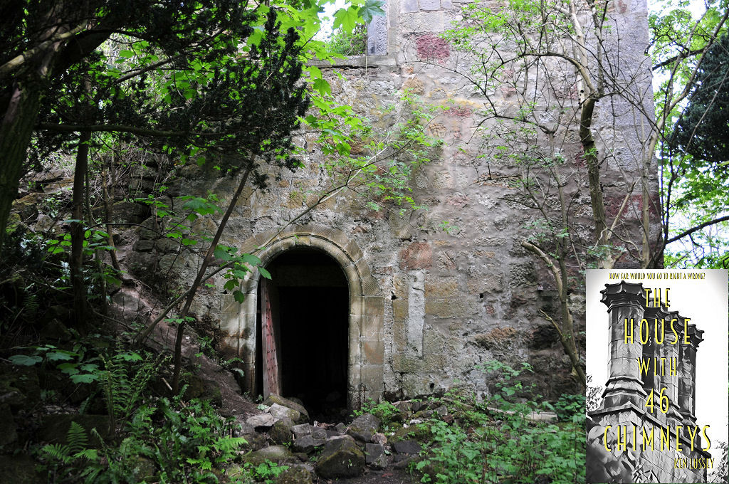 The image shows the lowest level of a stone tower with trees growing close to and around it. The tower is in sunshine. There’s an arched doorway leading through to a dark interior and a wooden door is open and leaning at an angle. The upper floor is ruinous. The front cover of ‘The House With 46 Chimneys’ is shown in the bottom right corner. 