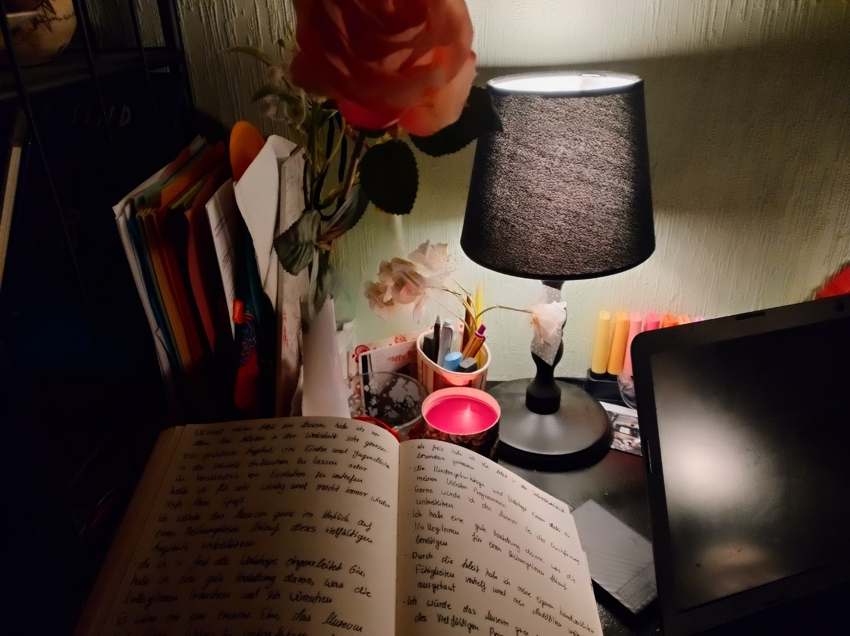 My desk with notebook, laptop, paperwork 
,a candle and flowers.