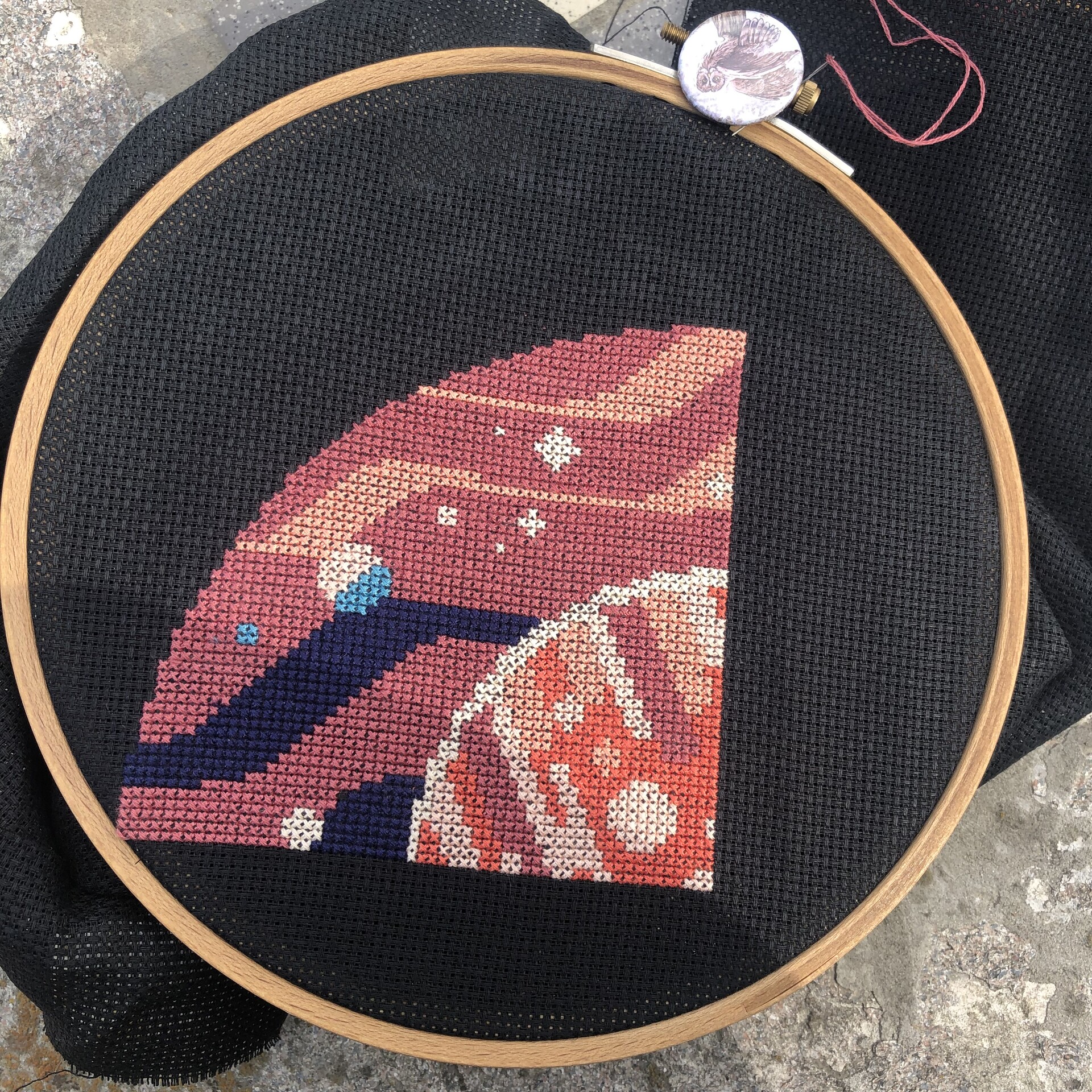 A quarter-circle portion of a circular cross stitch in progress, depicting a red planet in space, in modern geometric style 
