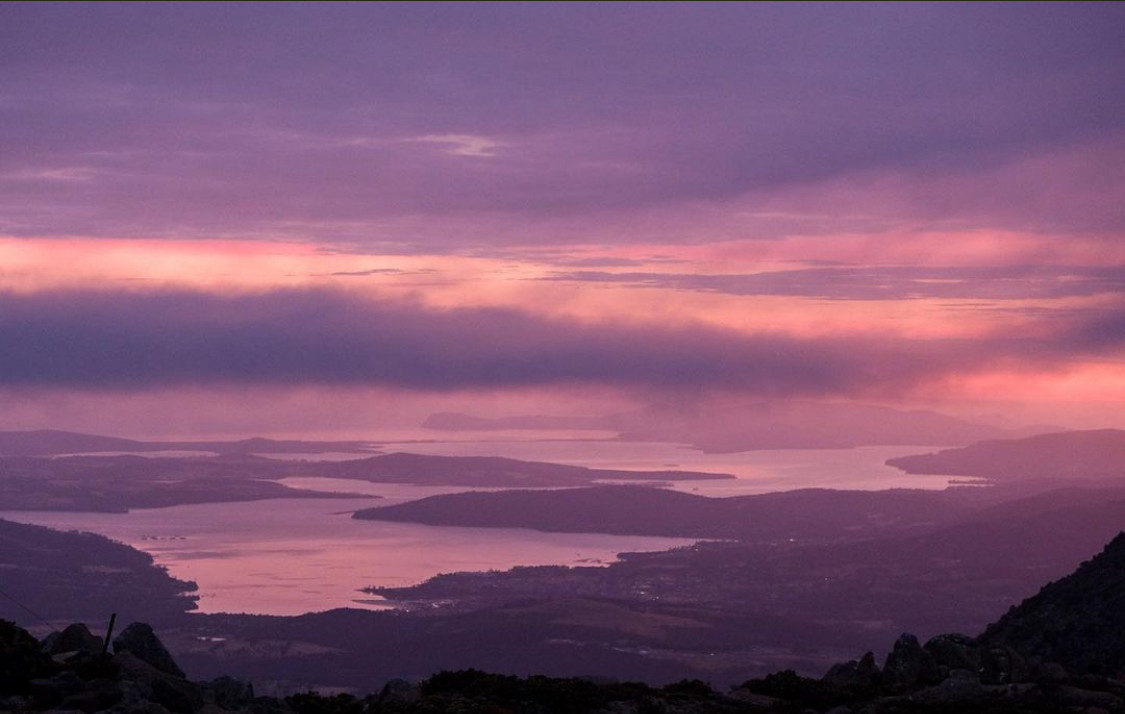 Sunset of pinks and purples. Looking out over water and land and sky. 