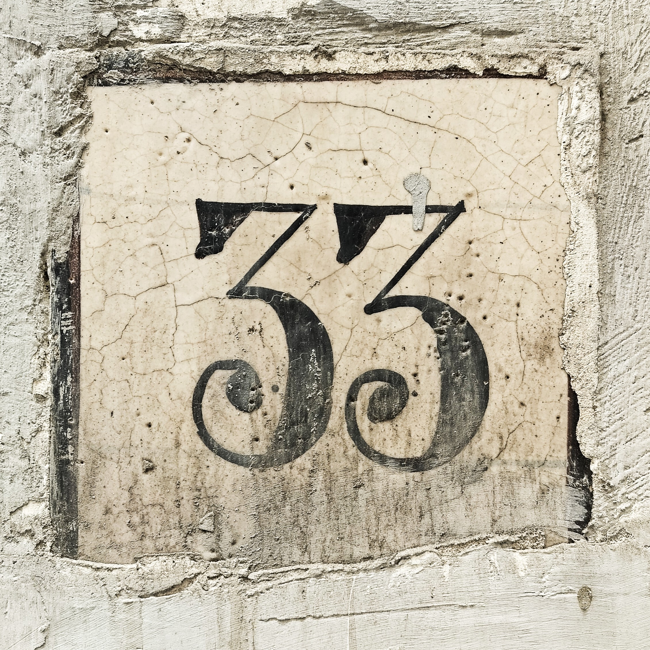 The number 33 in a very high contrast serif with flat-topped 3's and swirly ball terminals. The numbers are clearly hand-painted showing slight differences between them.